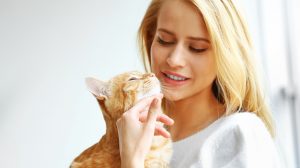 szőke nő vörös macskát simogat