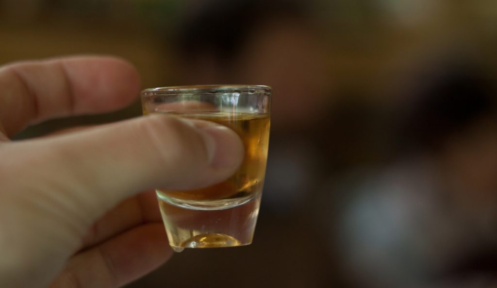 pálinkás poharat tart a kezében egy férfi