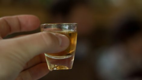 pálinkás poharat tart a kezében egy férfi