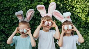 húsvéti nyuszis fülekkel gyerekek tojást tartanak a szemük elé aranyosan