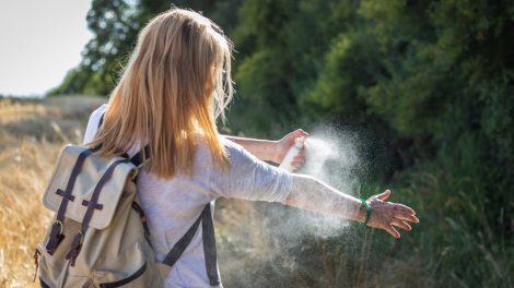 kullancsriasztó spray-t fúj magára a szőke nő az erdőben