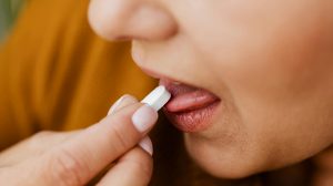 nő sárga pulcsiban vitamint vesz be