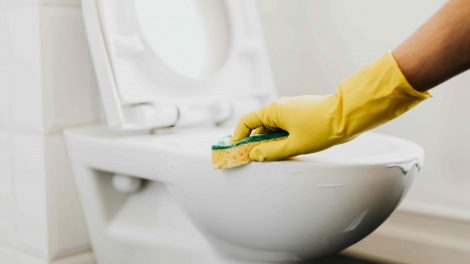nő gumikesztyűben súrolja a wc-t