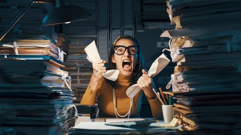 Dühös, stresszes dolgozó túlterhelt papírmunkával