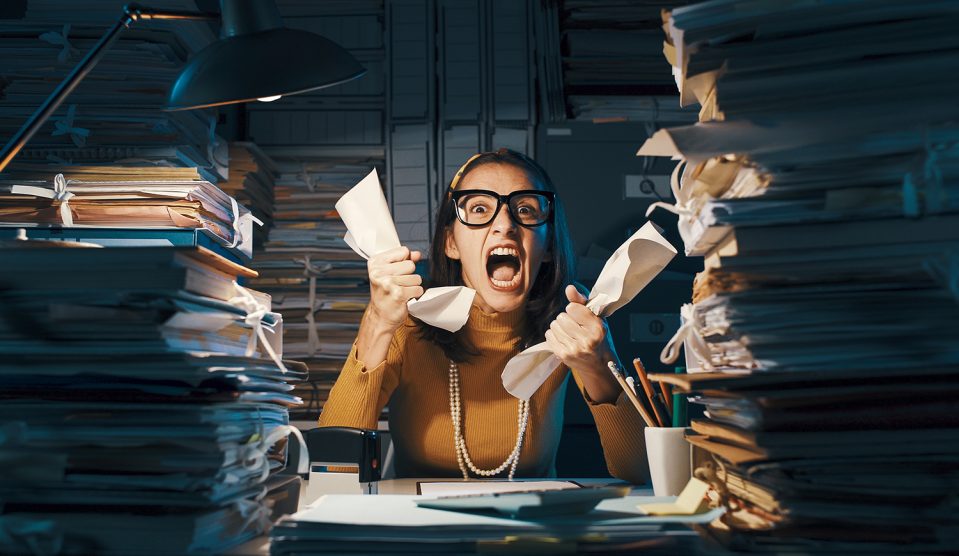 Dühös, stresszes dolgozó túlterhelt papírmunkával