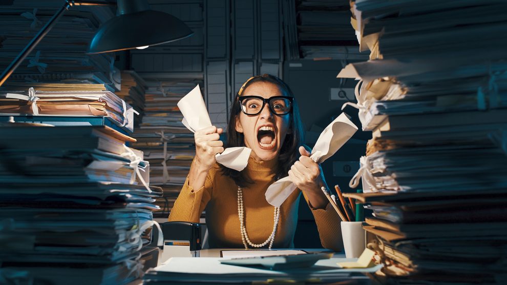 Dühös, stresszes dolgozó túlterhelt papírmunkával