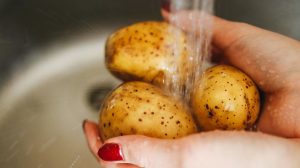 nő mossa a krumplit a mosogatóban