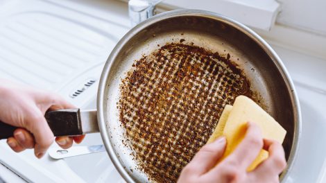 odaégett serpenyőt mosogat egy nő sárga mosogatószivaccsal
