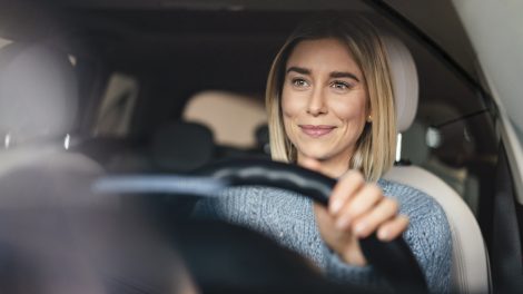 mosolyogva vezet autót egy nő