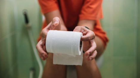 wc-n ül egy nő wc-papírt tart a kezében