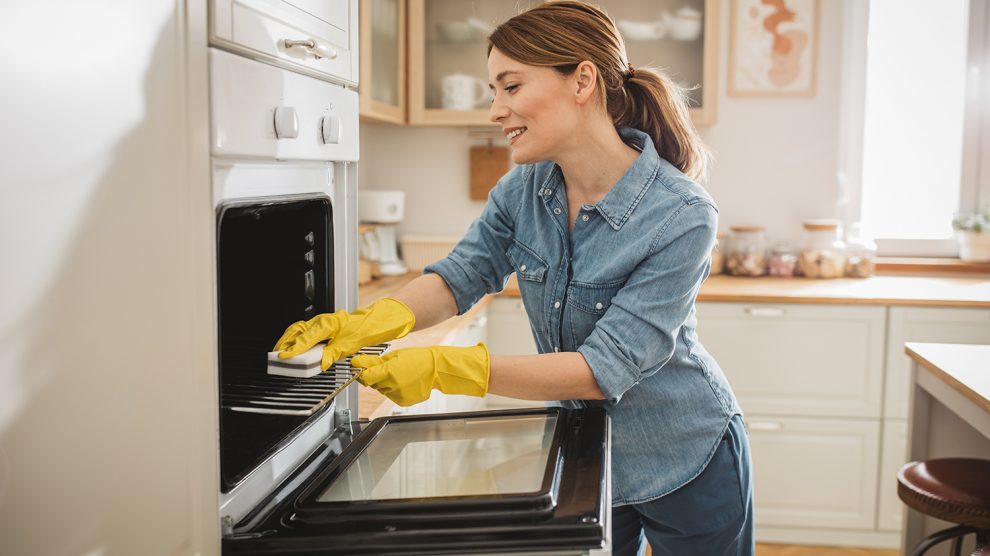 Fiatal nő takarítja a sütőt