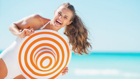 Boldog fiatal nő fürdőruhában, strandkalapban