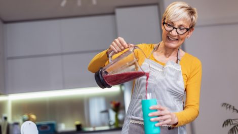 áfonya turmixot készít a konyhában egy idős hölgy