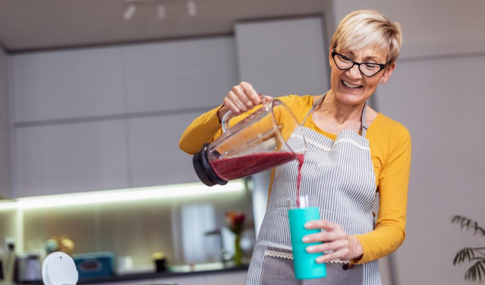 áfonya turmixot készít a konyhában egy idős hölgy