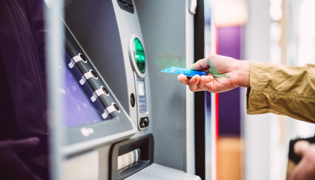 bankkártyát dug a bankautomatába egy nő