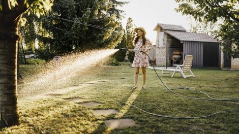 kánikulápan locsolja a gyepet füvet egy lány