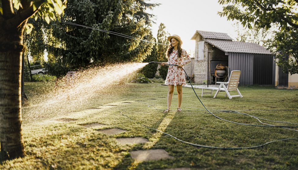 kánikulápan locsolja a gyepet füvet egy lány