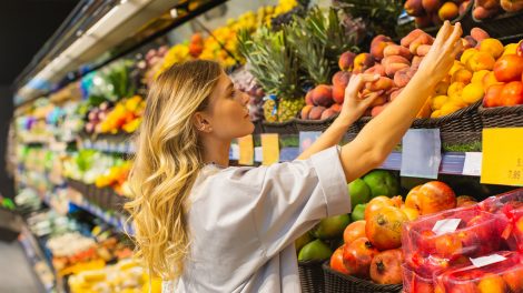 zöldséget és gyümölcsöt válogat egy nő a boltban
