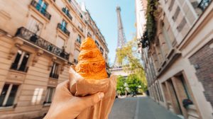 Croissant-t tartó kéz az Eiffel-toronynál