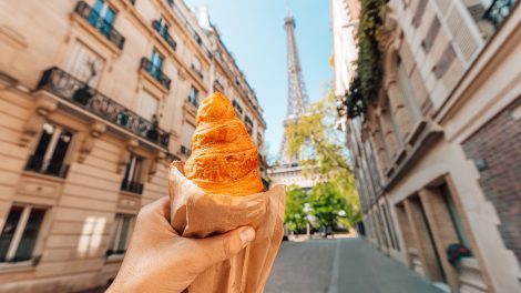 Croissant-t tartó kéz az Eiffel-toronynál
