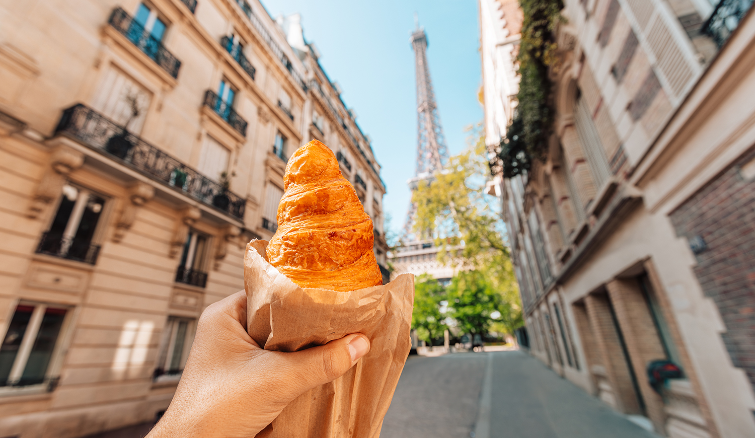 Croissant-t tartó kéz az Eiffel-toronynál