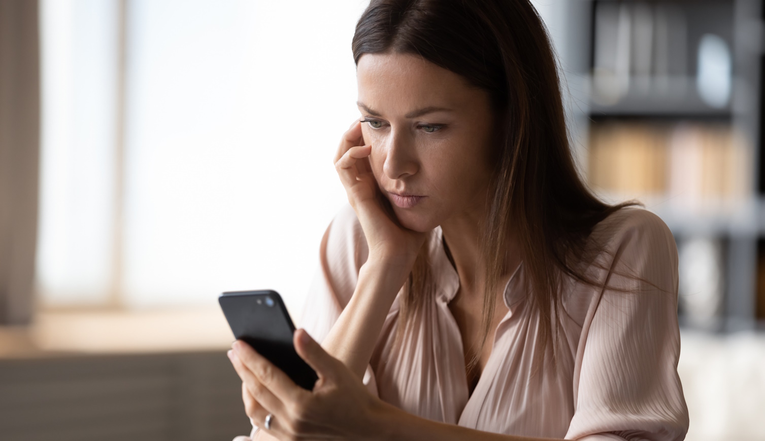 fiatal nő bosszankodva nézi a telefonját