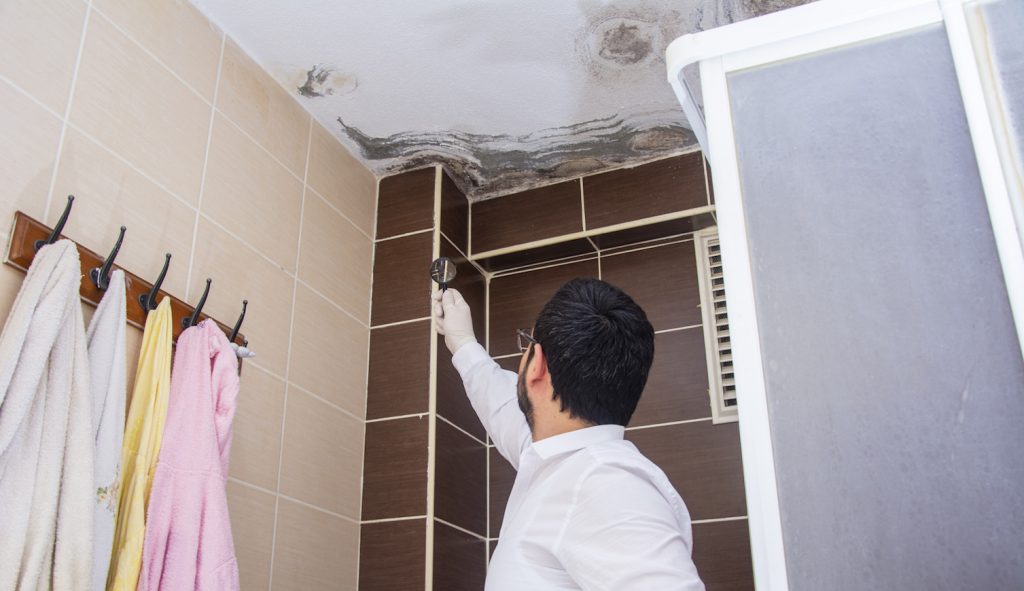 penész a fürdőszoba plafonján nézi egy férfi