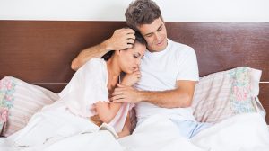 Férfi vigasztalja feleségét az ágyon ülve a hálószobában
