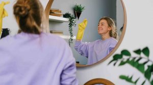 nő gumikesztyűben mosolyogva takarít