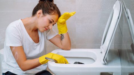 sárga gumikesztyűben wc-t takarít egy fiatal lány