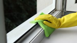 ablakkeretet pucol egy nő sárga gumikesztyűben