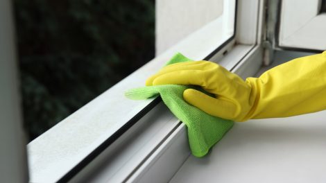 ablakkeretet pucol egy nő sárga gumikesztyűben