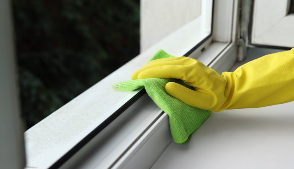 ablakkeretet pucol egy nő sárga gumikesztyűben
