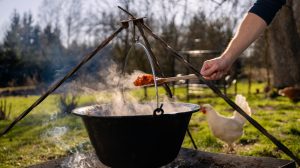 férfi fakanállal bográcsos pörköltet kever