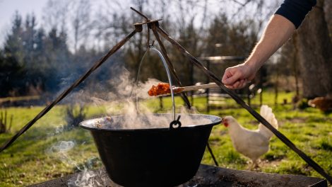 férfi fakanállal bográcsos pörköltet kever