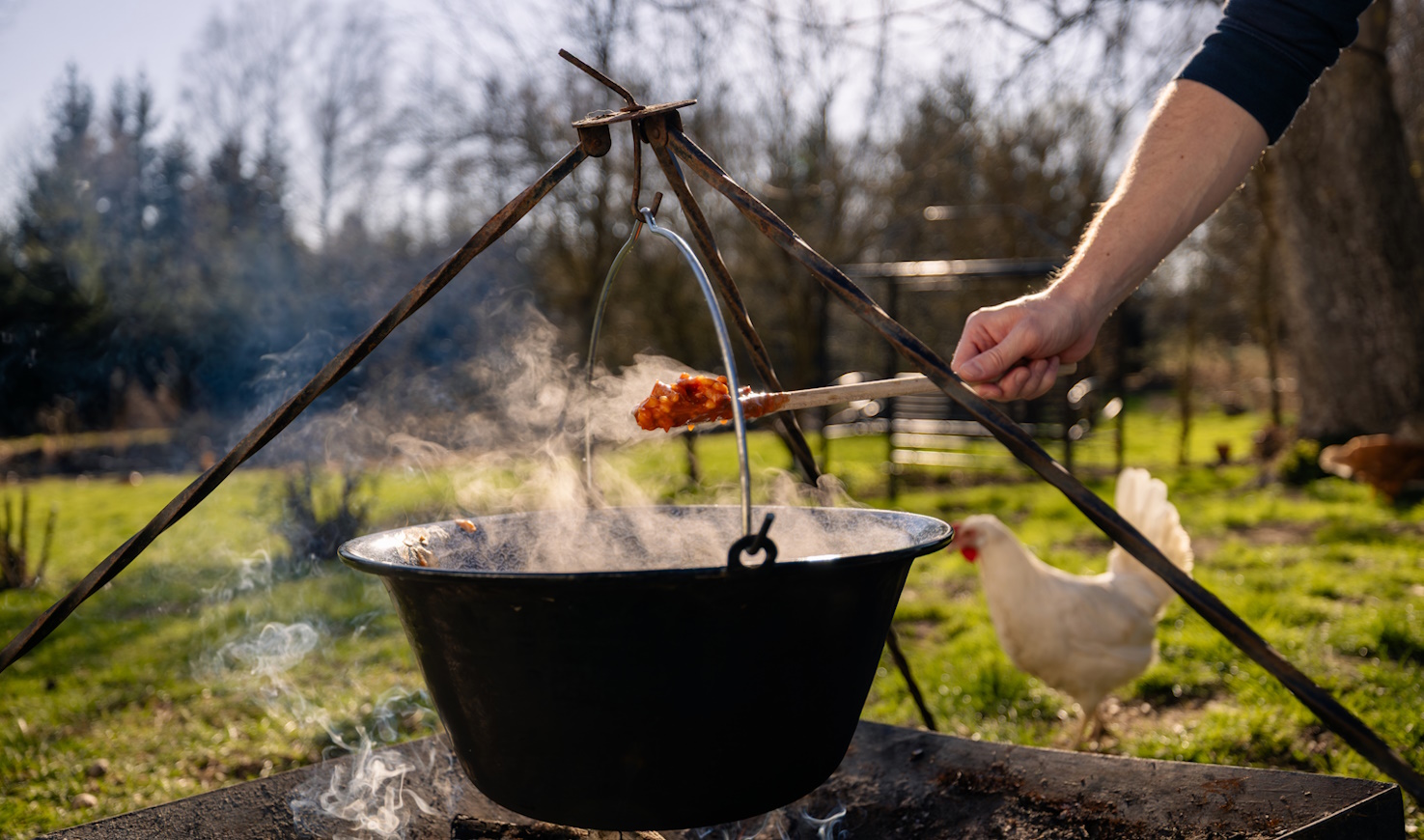férfi fakanállal bográcsos pörköltet kever