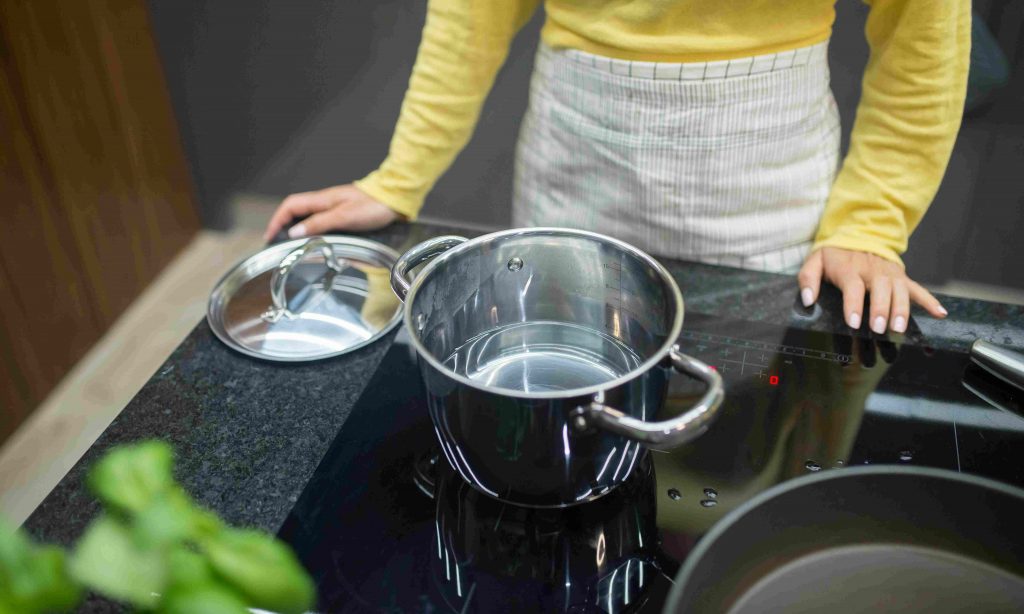 nő vizet forral indukciós főzőlapon