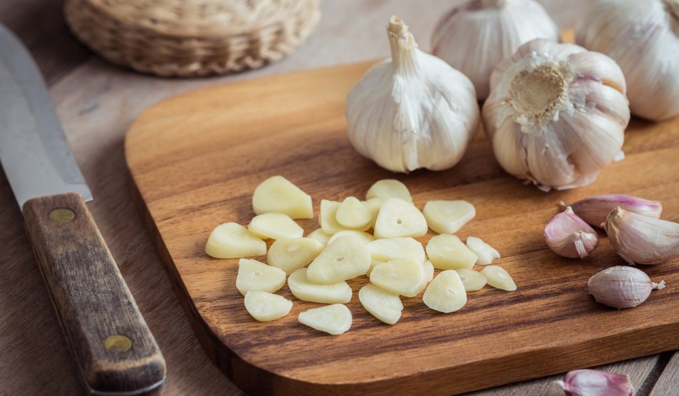 Egy tálcán felszeletetlt fokhagyma, mellette pedig egy teljes fokhagymafej