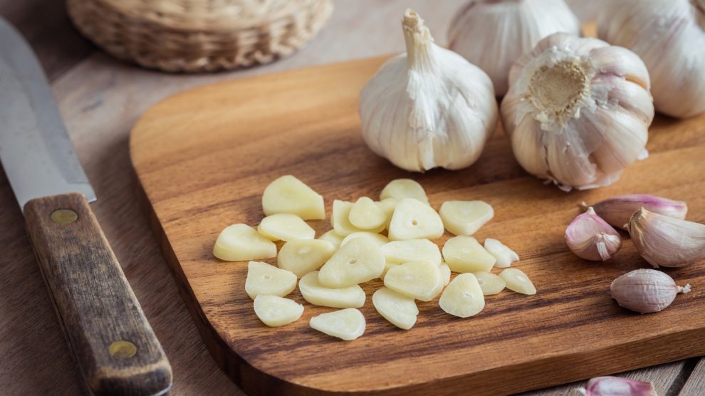 Egy tálcán felszeletetlt fokhagyma, mellette pedig egy teljes fokhagymafej