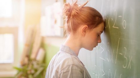 vörös kislány az iskolai táblánál áll mérgesen