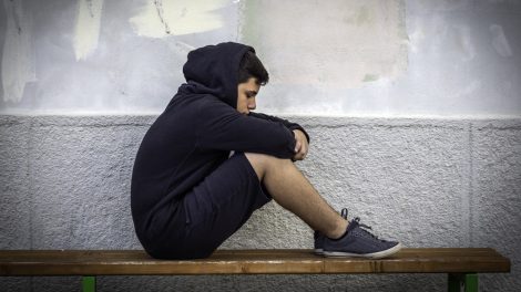 szomorú iskolás fiú a padon