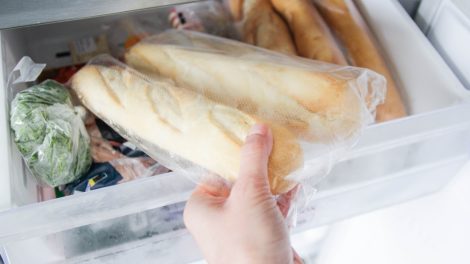bagettet tesz a fagyasztóba egy nő
