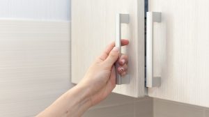 nő kinyitja a konyhaszekrényt