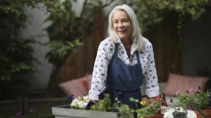 idősebb hölgy virágokat ültet át ősszel