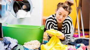 nő mosógépből kiveszi a ruhákat