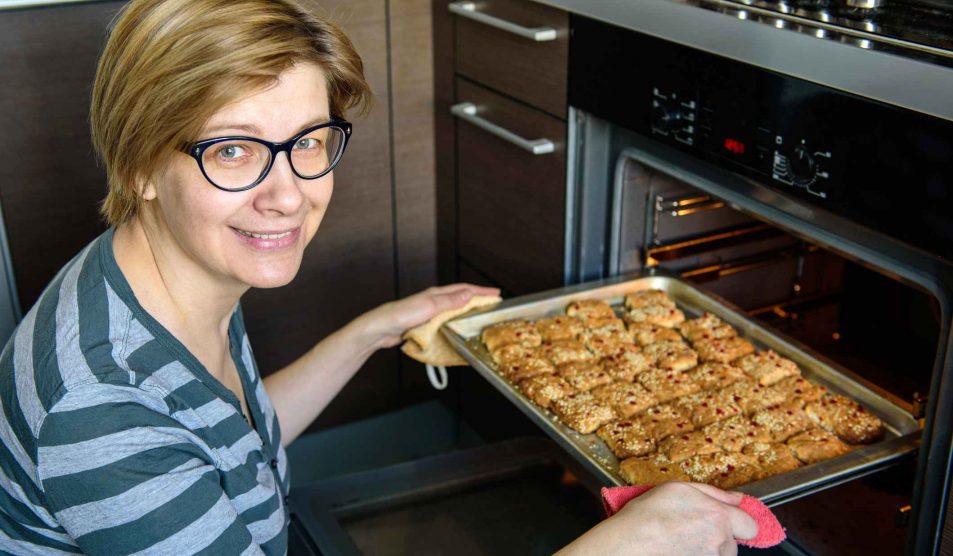 nő kiveszi a sütőből az ételt