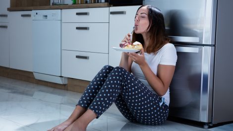 nő kéjesen tortát eszik a konyhapadlón ülve