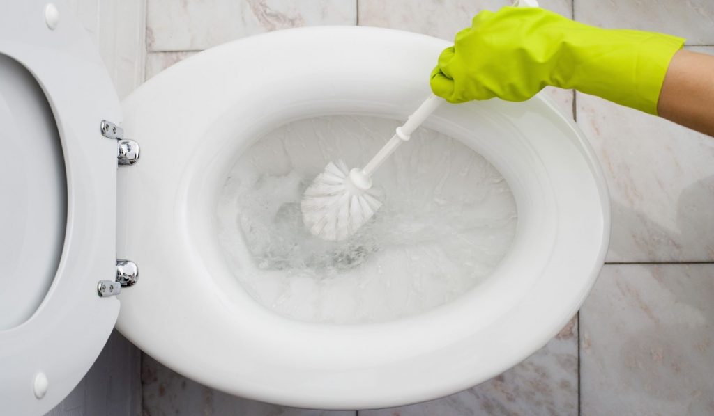 nő gumikesztyűben súrolja a wc-t
