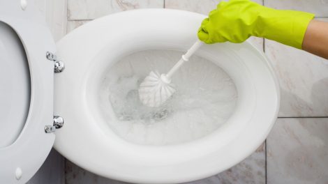 nő gumikesztyűben súrolja a wc-t