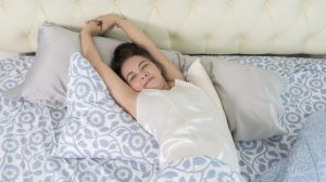 nő ébredés utén nyújtózkodik az ágyban